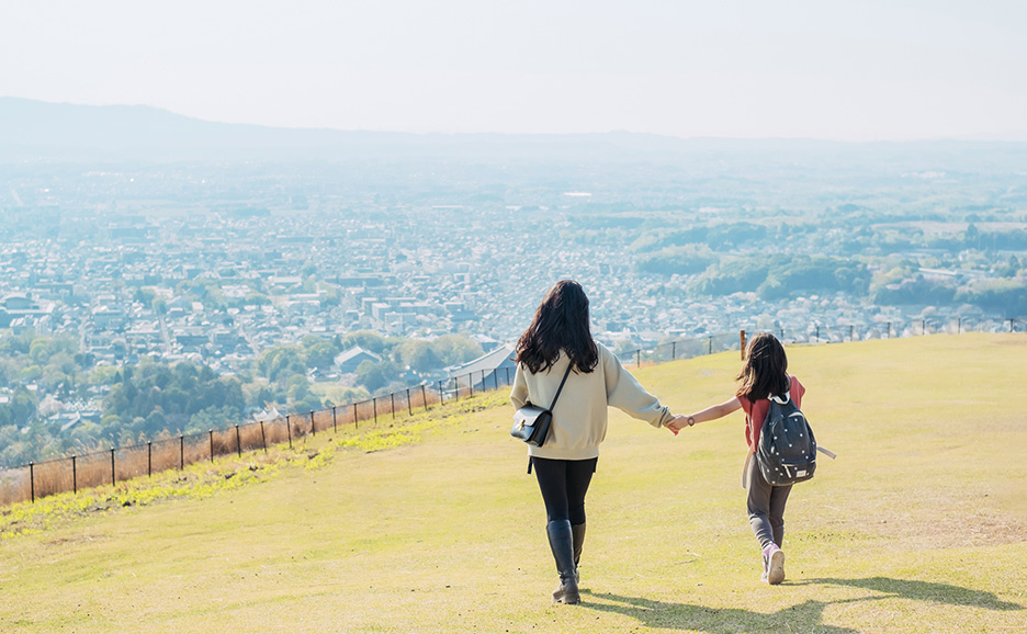 A mother and a daughter looking at the city from the mountain
