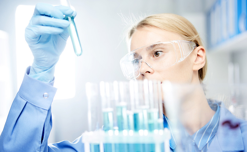 A female chemist who stares at a test tube in the lab
