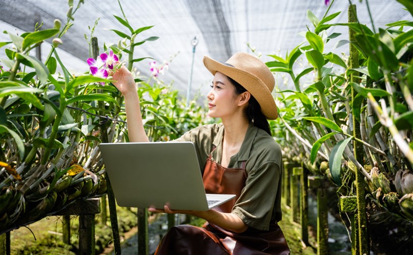 A woman in a greenhouse holding a computer