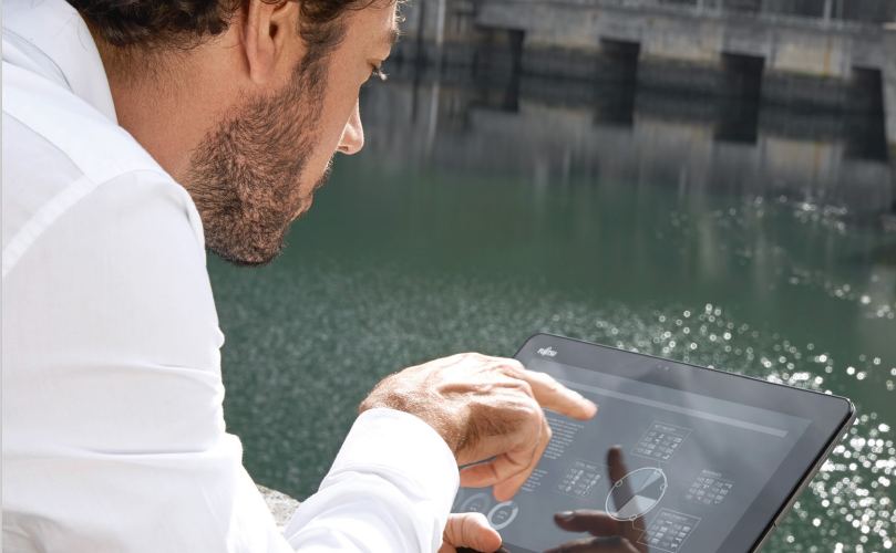 水辺でタブレットを操作する男性ビジネスマンの写真