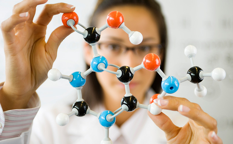 分子構造の模型を見ている女性化学者
