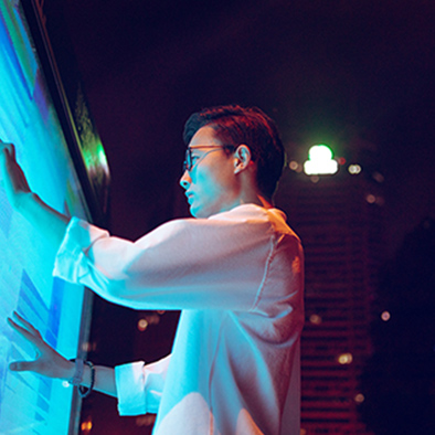 A man in a white shirt and glasses using a large touch-screen display