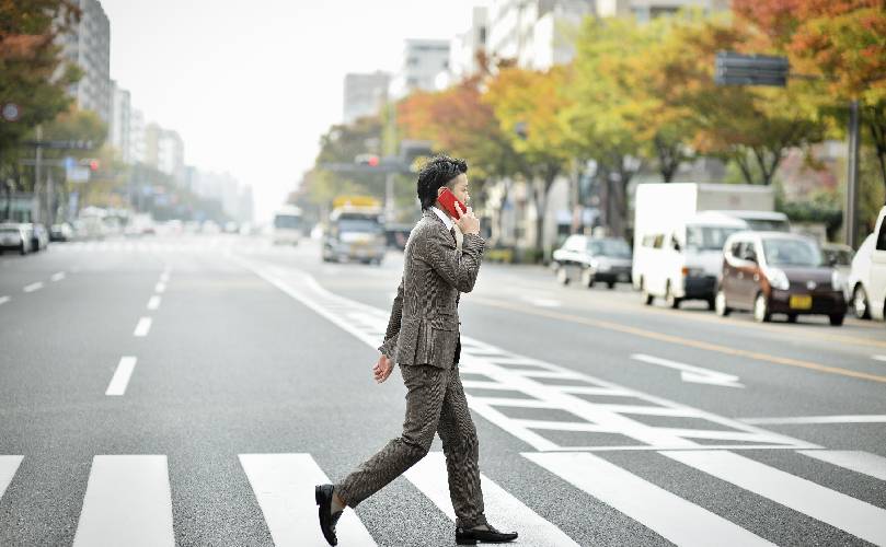  City environment and a businessman using the smartphone, on zebra crossing