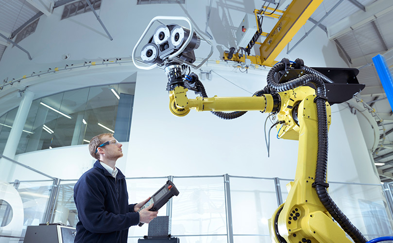 A person operating a robot in a digital manufacturing plant